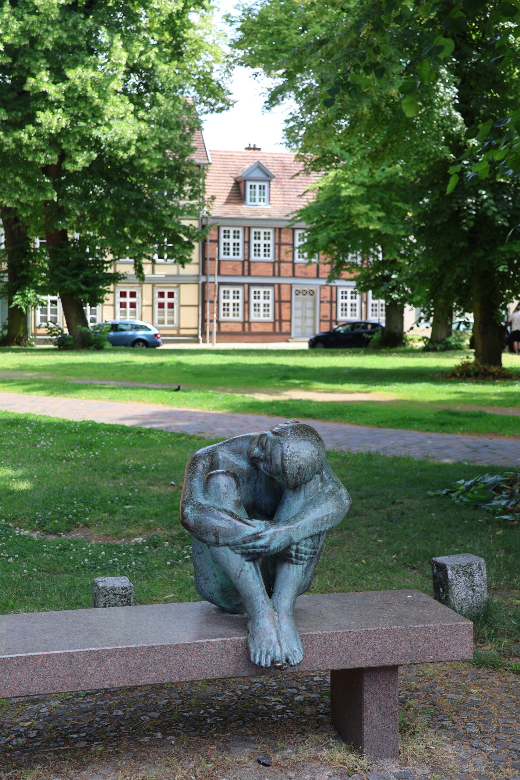 Skulptur „Die Sitzende“ von August Martin Hoffmann auf einer Bank vor der Schelfkirche St. Nikolai in Schwerin