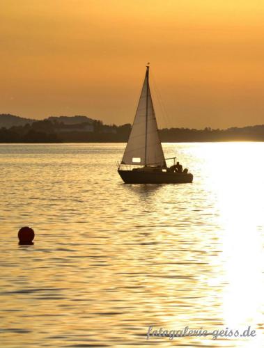Segelboot-im-Sonnenuntergang-am-Chiemsee-im-Strandbad-Uebersee-fotografiert